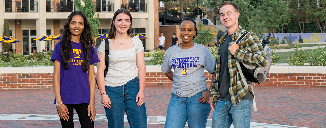 Students stand and smile together outside the Student Activities Center