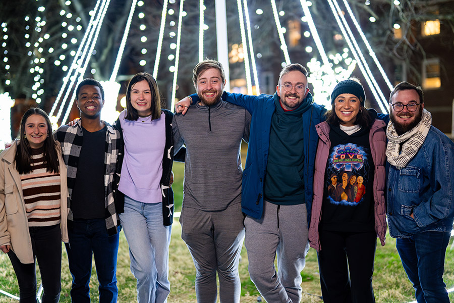 A group of students posting in front of a string of lights.
