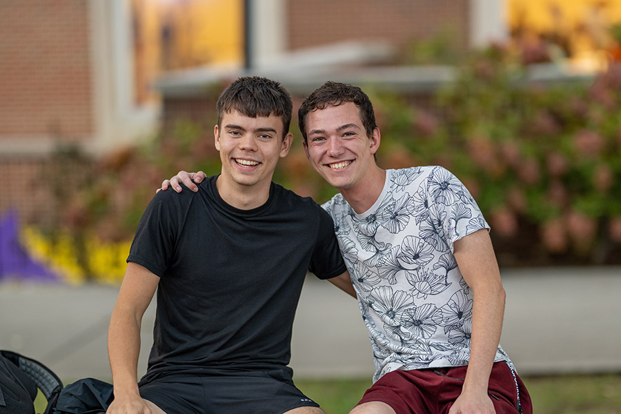 Two students posting for the camera, sitting on a bench on the Plaza.