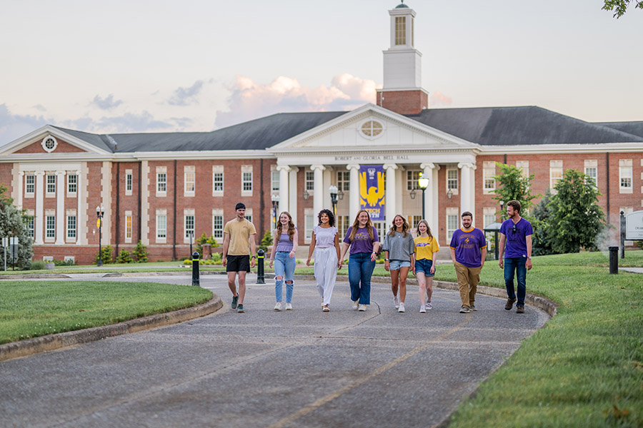 A group of students walking side by side in front of Bell Hall.