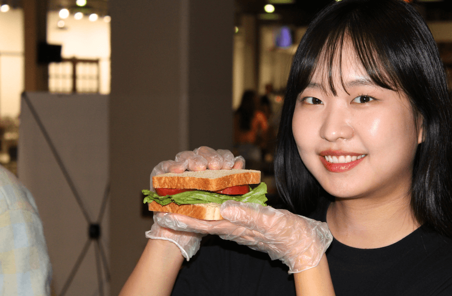 A student holding up a sandwich created in Teaching Kitchen.