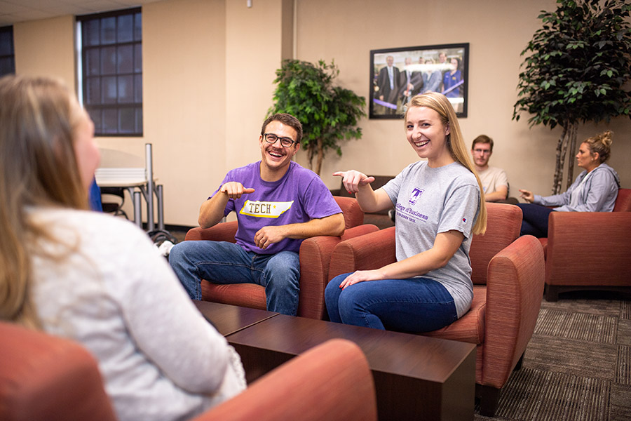 Two smiling students giving a "Wings Up" to the camera. 