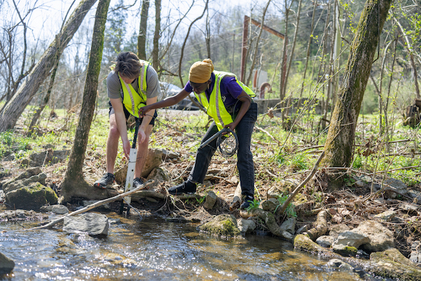 Students collect stream data using field equipment during a hands-on water quality research activity.