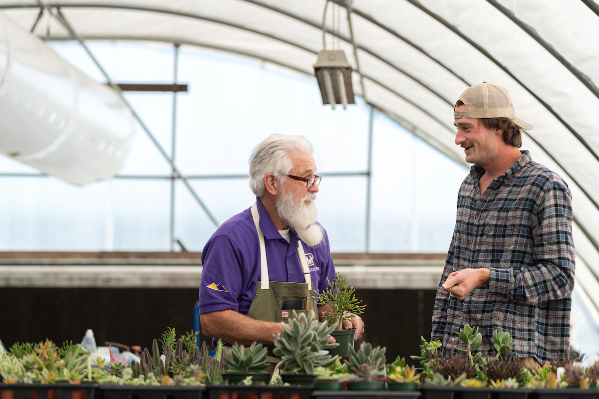 Student and instructor discuss plant production while working with greenhouse-grown plants.