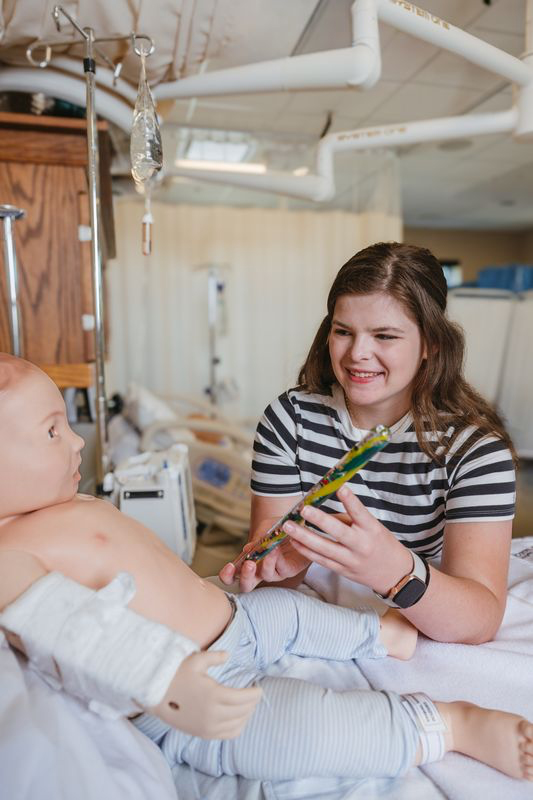 A student working with an infant dummy and smiling