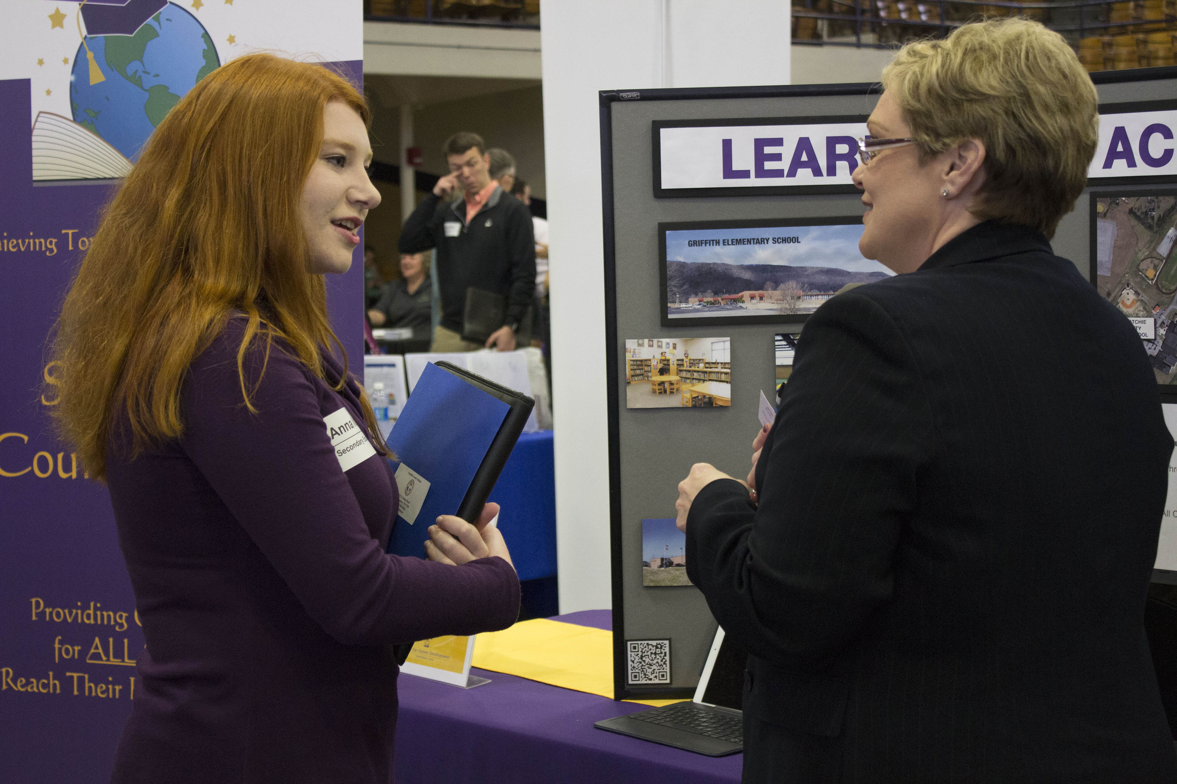 Photo of a student attending a career fair and speaking with an employer at their booth.