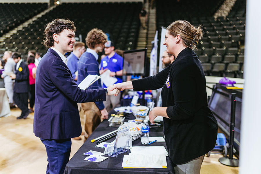 A student at a job fair shaking hands with with an employer.