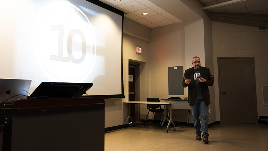 Presenter speaks in front of a large screen during the Reel Tech Film Festival, introducing a screening or festival event.