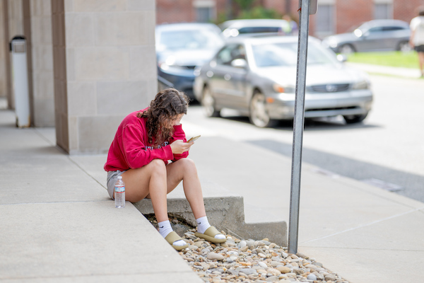 A student sits outside looking at her phone.