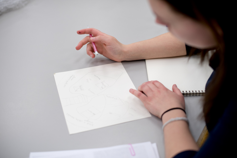 Student drawing a picture while sitting at a table.