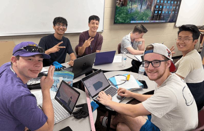 Male GSET Students smile for picture as they work on a project