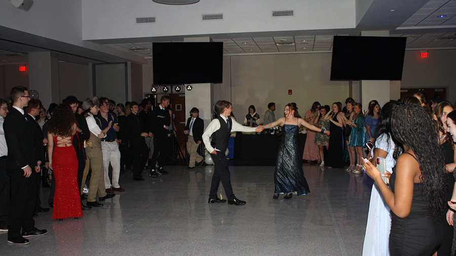 A couple students dancing as other watch.