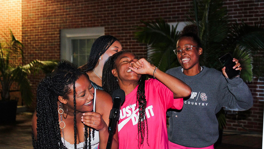 Four students laughing during an on-campus event.