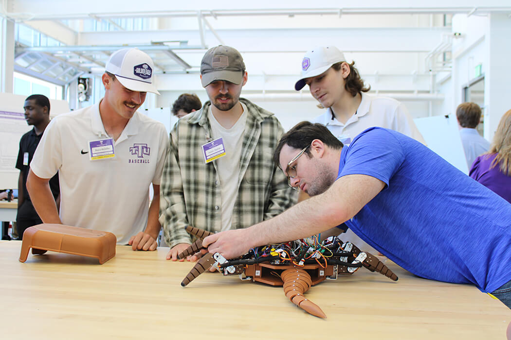 A photo of a student working on his capstone project at the Senior Design Expo.