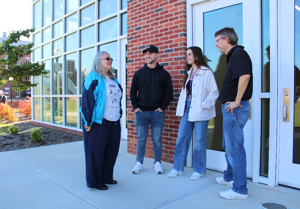 Dr. Boshart and Dr. Kosa standing in front of Bruner Hall talking to students.