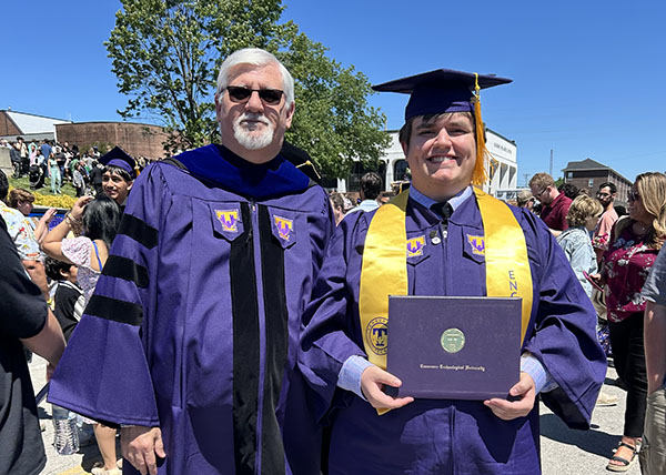 Dr. Eric Brown and a graduating student standing outside Hooper Eblen Center on commencement day. 