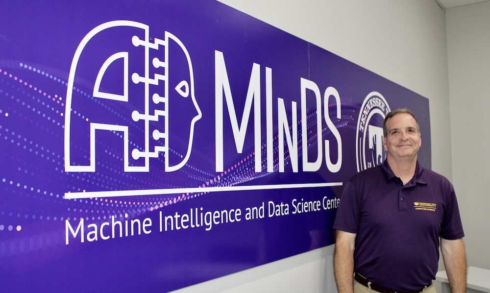 Dr, Toug Talbert stands in front of MInDS wall sign