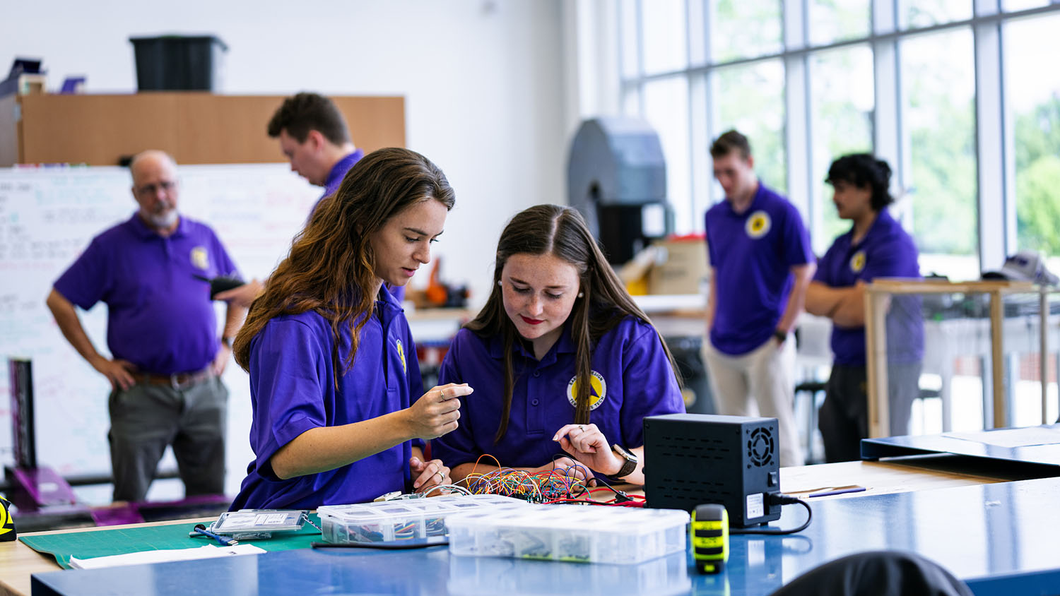 Two female students in a class at a work station.