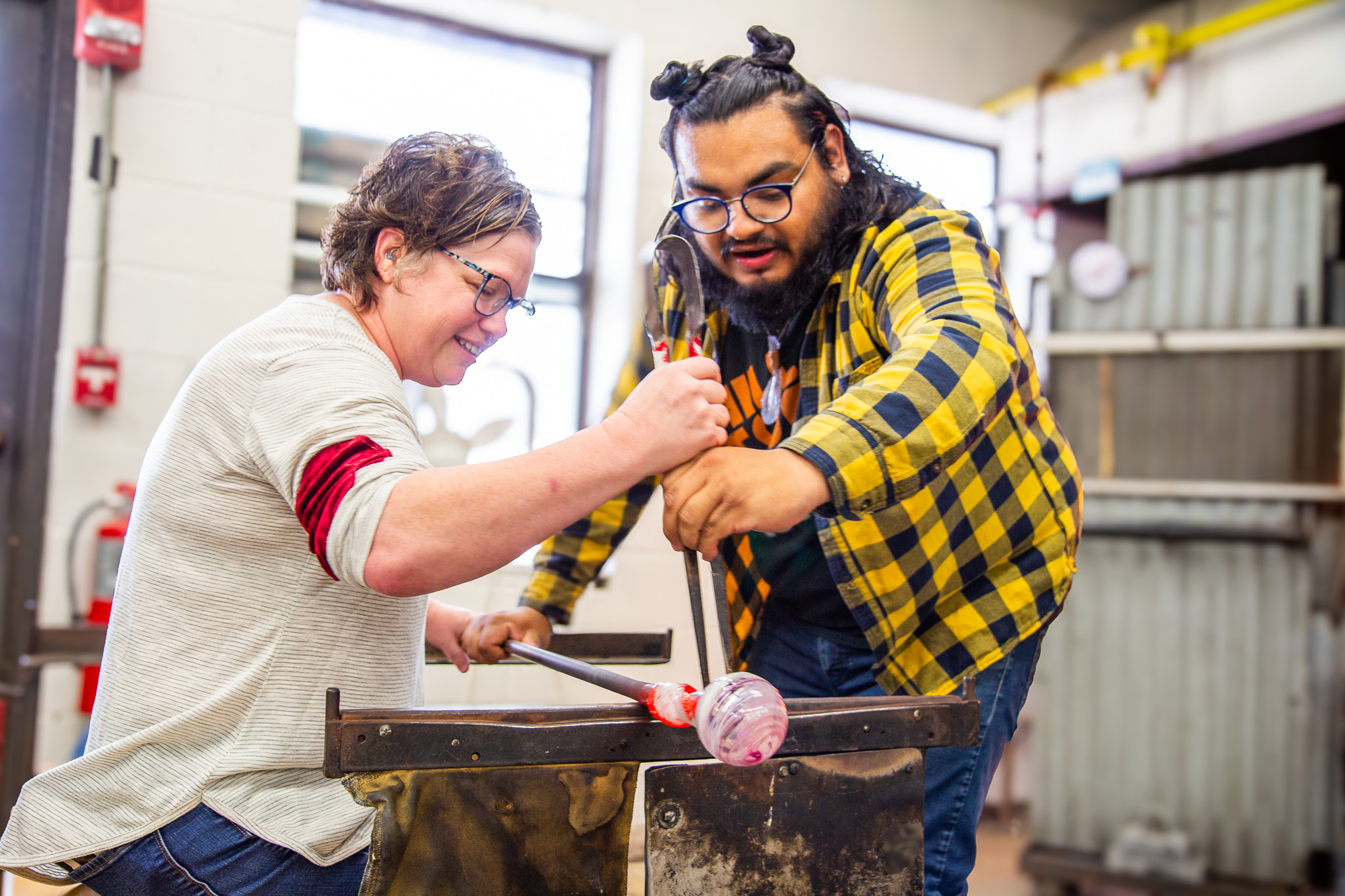 two people glassblowing an ornament