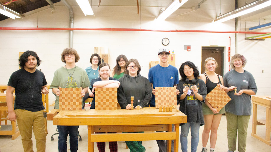 A group of students posing with their wood studio projects.