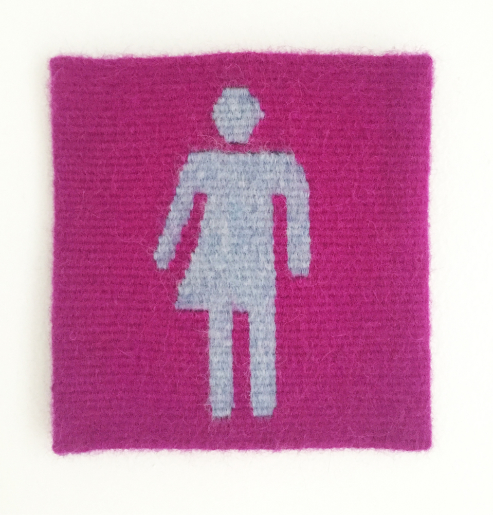 A pink patch of tapestry with a restroom gender sign