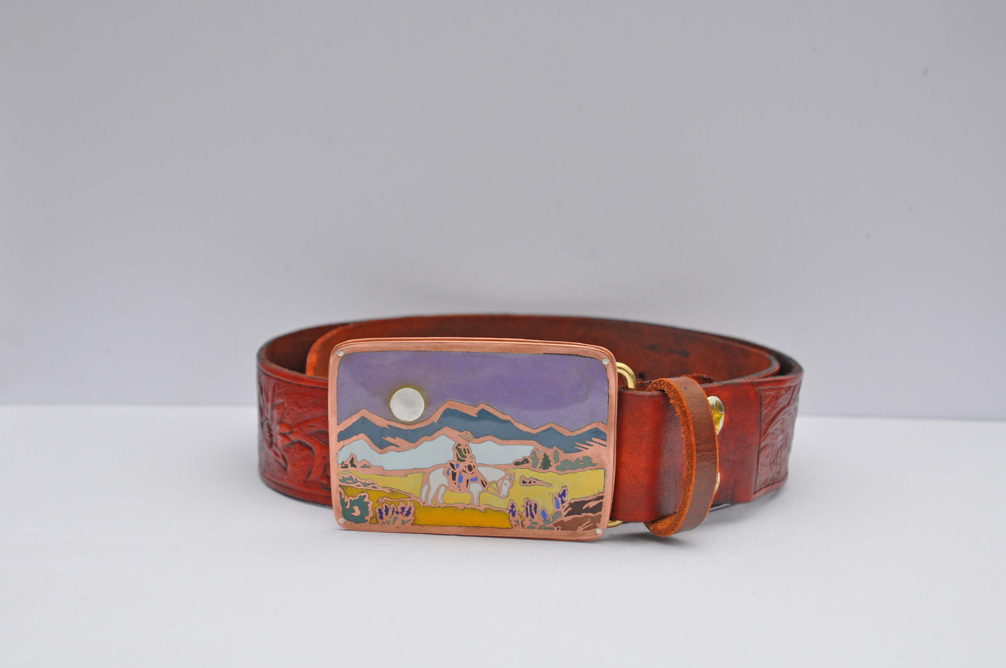 A belt with metal enameling designs on the buckle