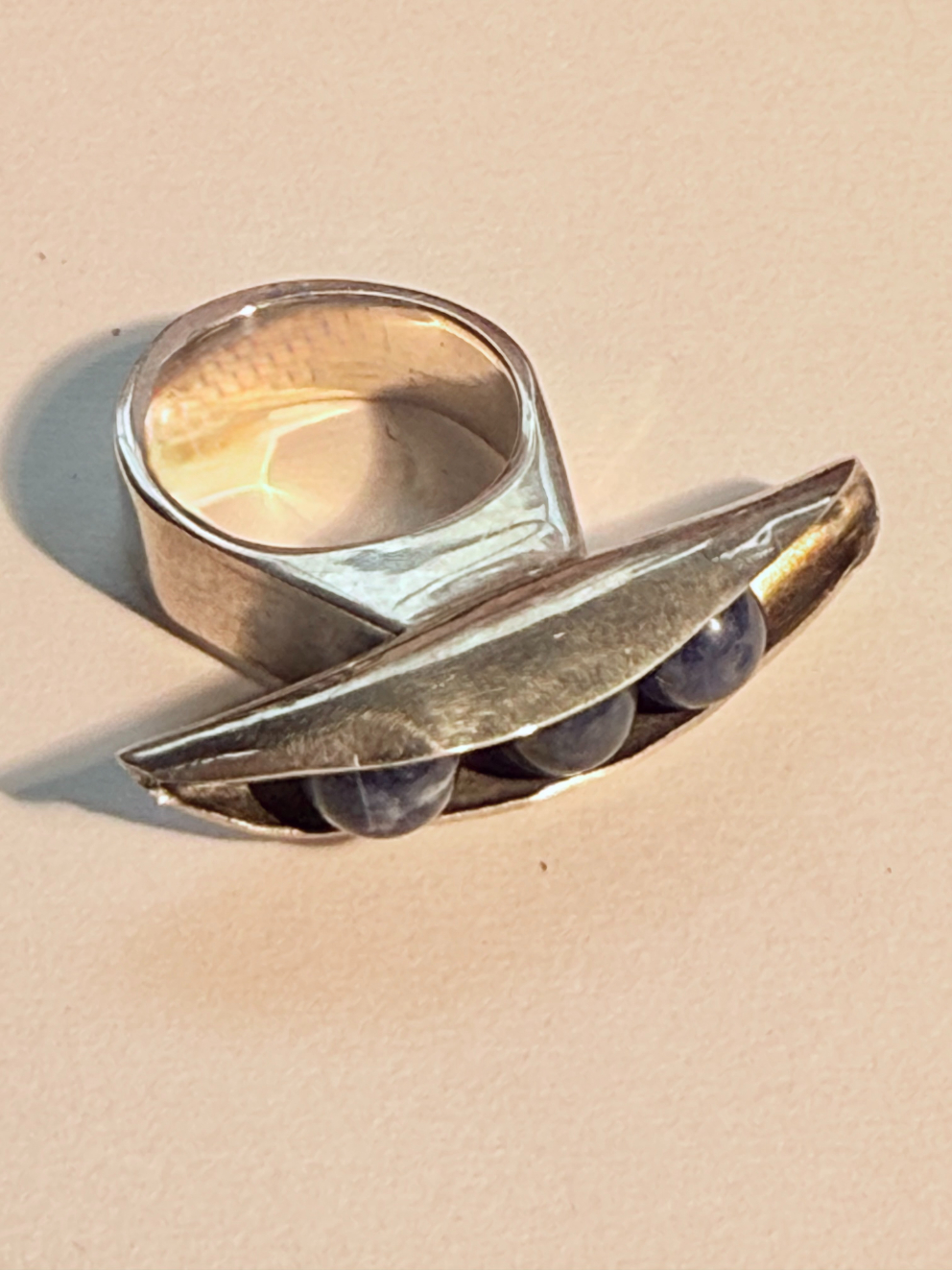 Silver ring with pea pod object on front of ring