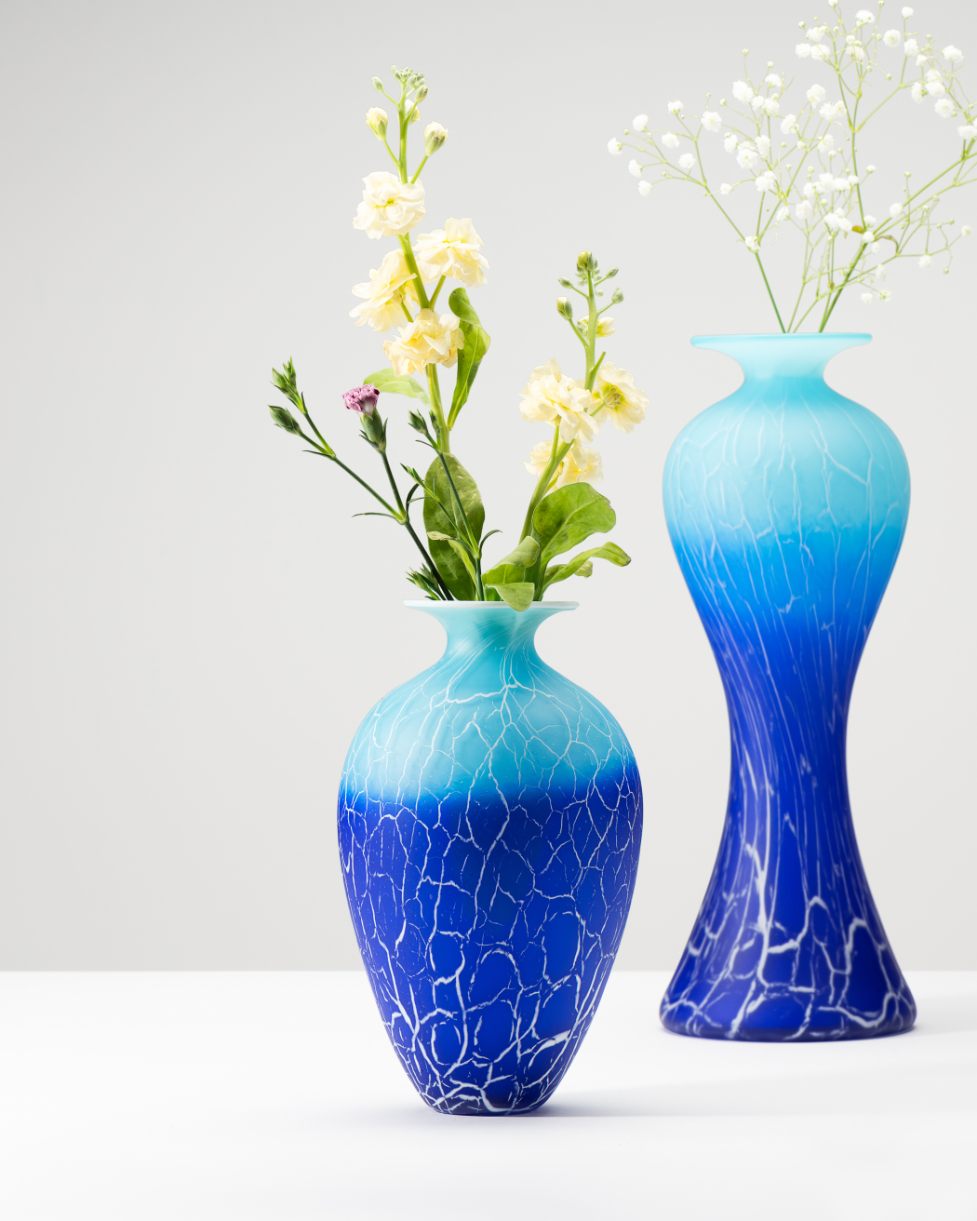 Two blue glass vases with flowers in them