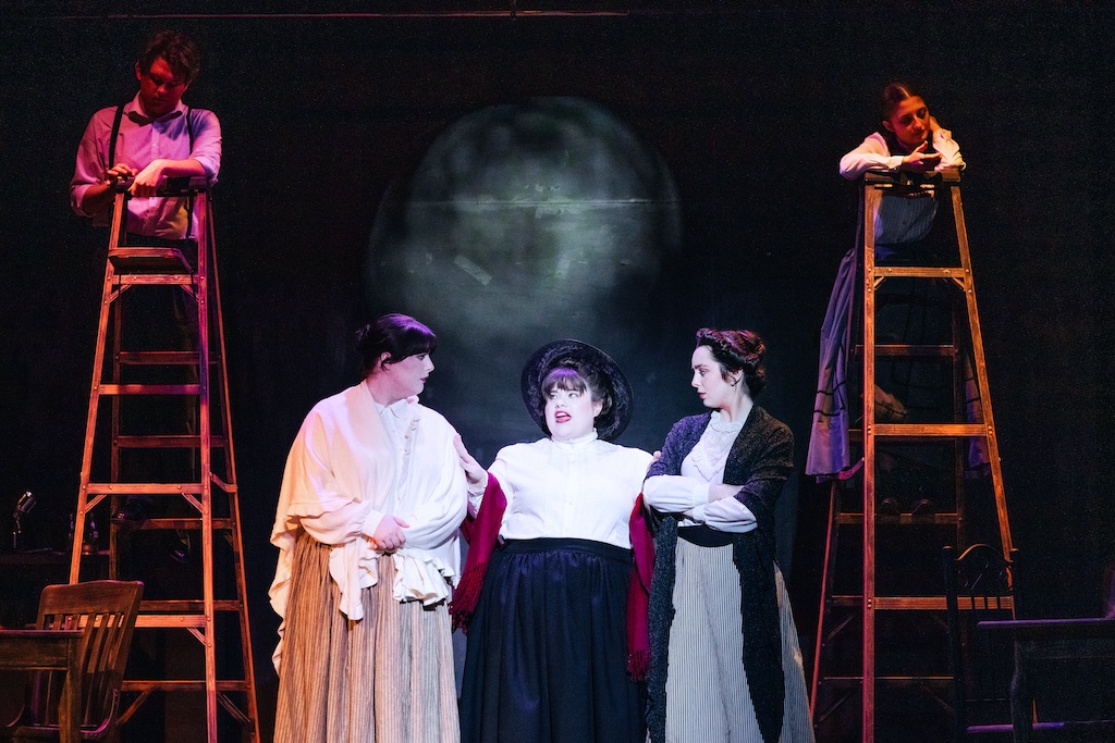 Mrs. Gibbs, Mrs. Soames, Mrs. Webb and George and Emily on ladders behind them, of Our Town, on stage at the Backdoor Playhouse 