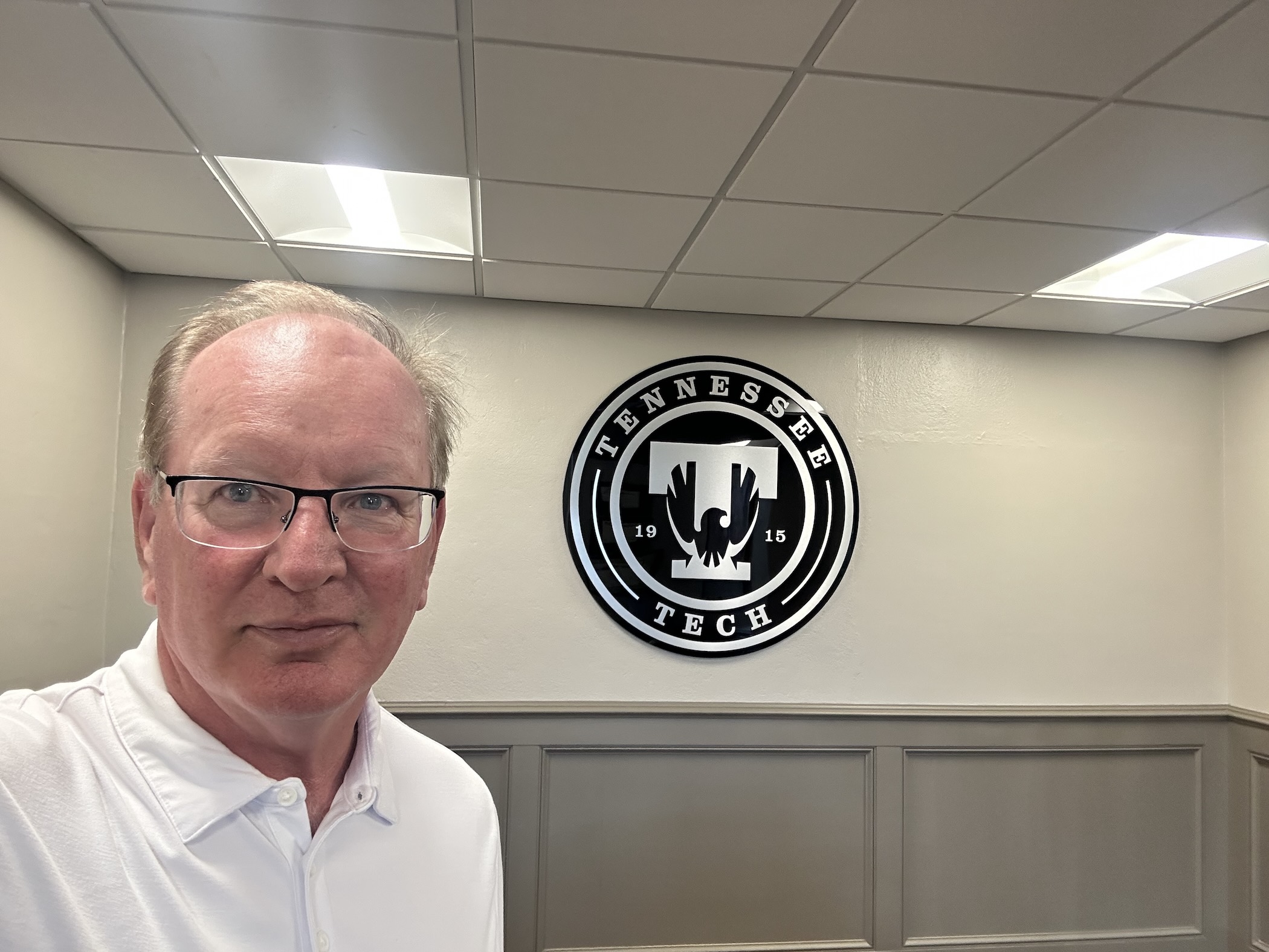 Mickey Latour is shown in a selfie photo in his new office. A Tech seal is seen in the background.
