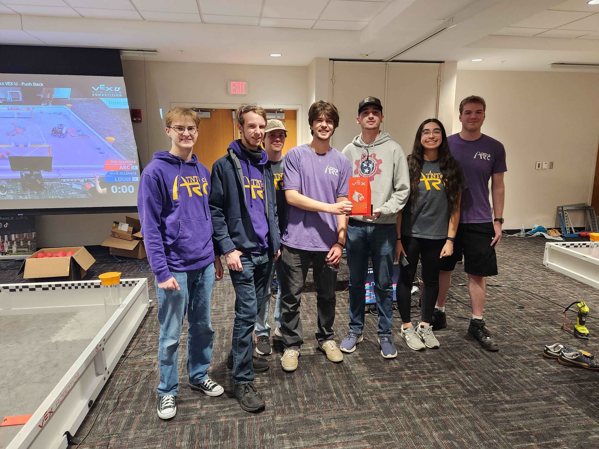 Students smile in a group photo and hold up an award.
