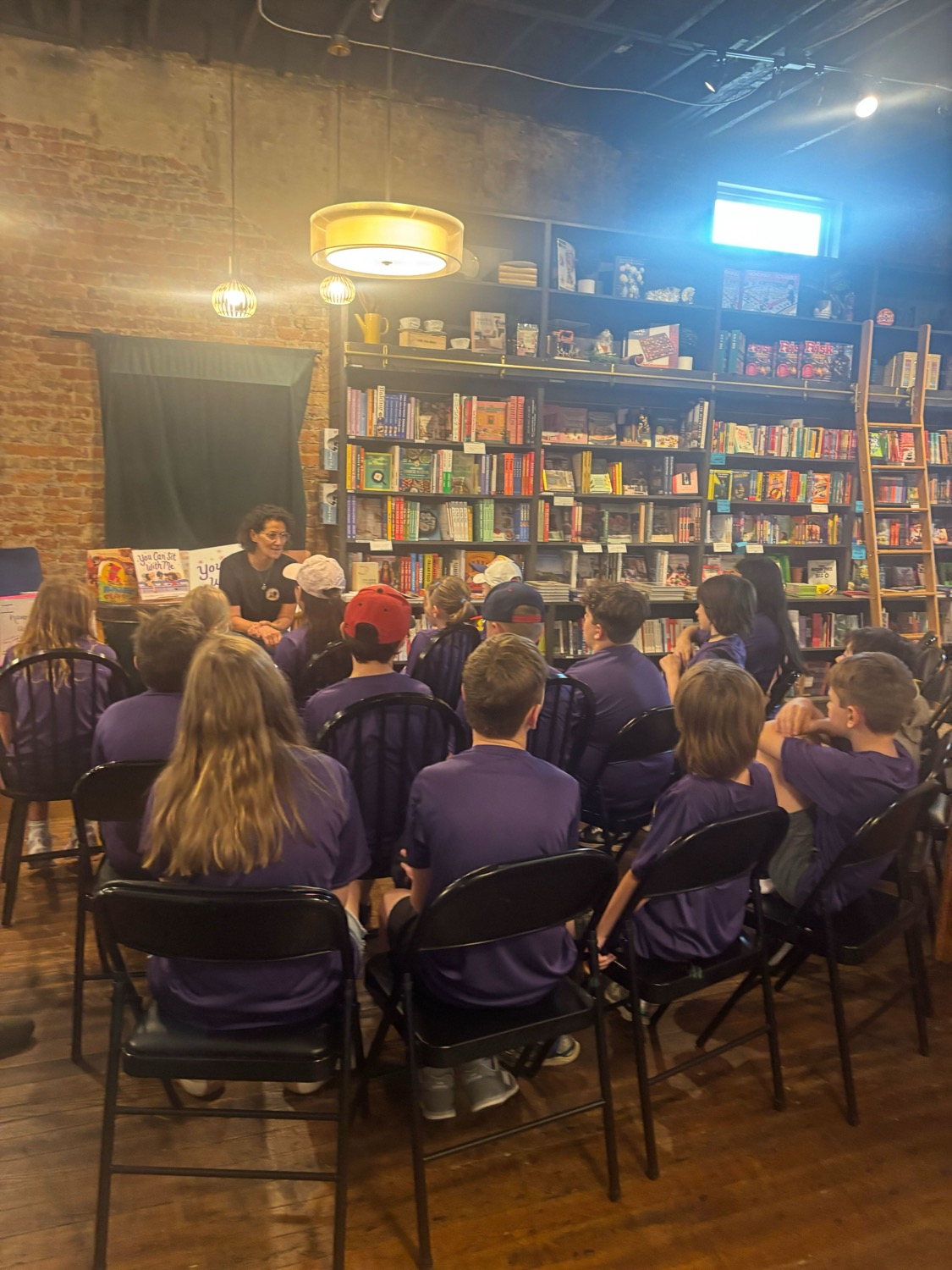 Students gather in chairs around author Rachel Tawil Kenyon as she speaks to the crowd.
