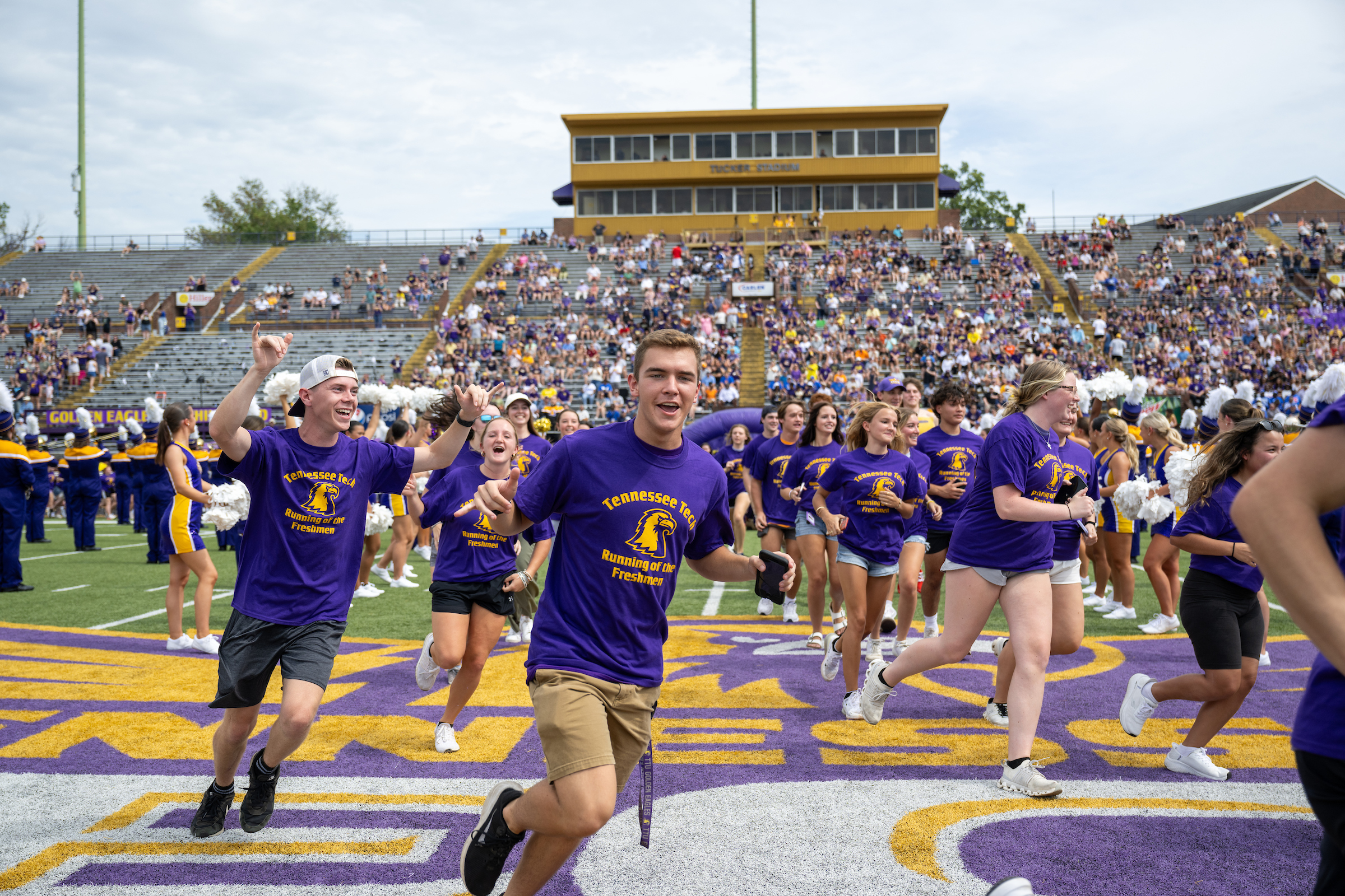 students running across the football field in purple Tech t-shirts during the Running of the Freshmen