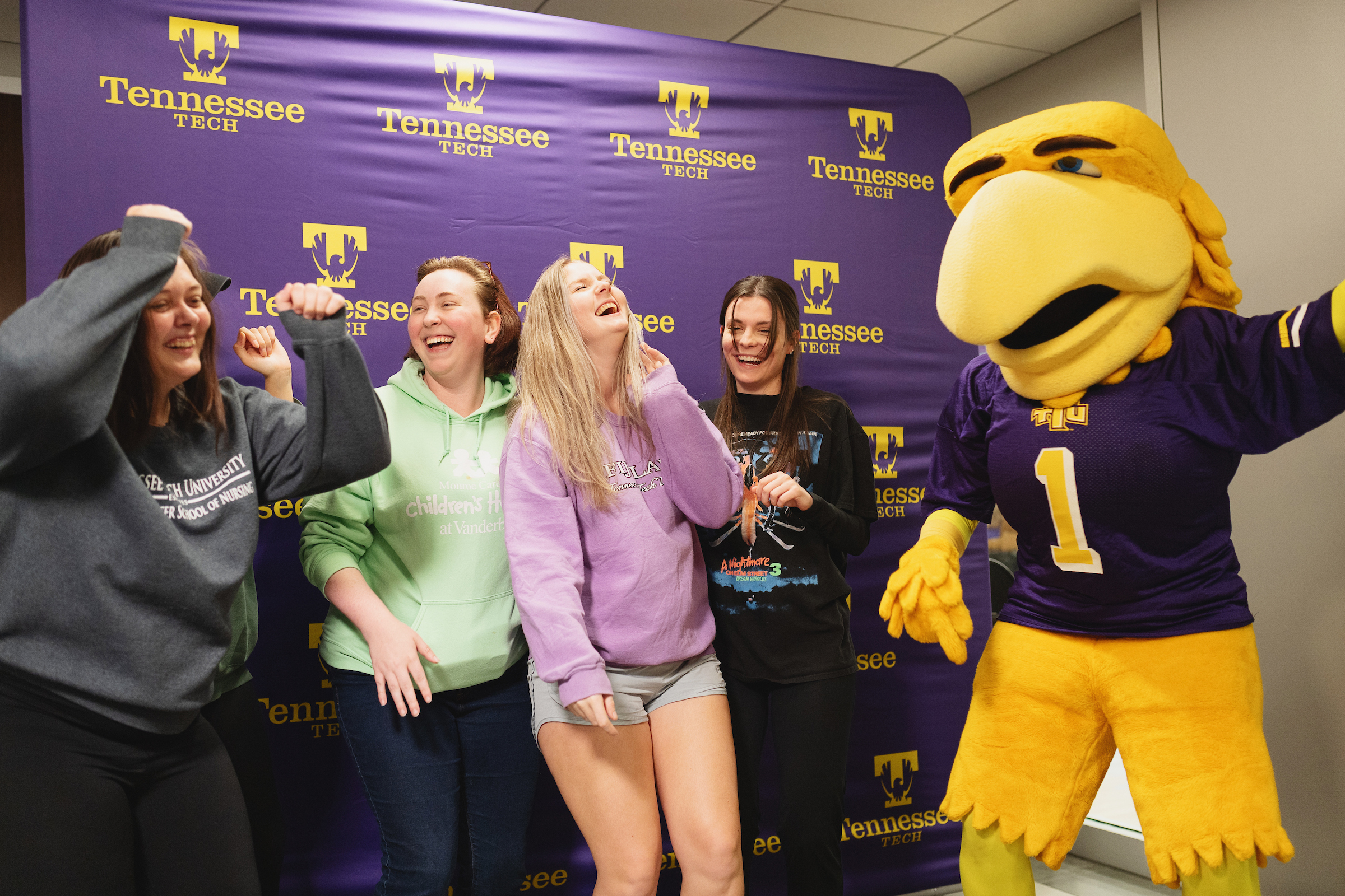 four female-presenting students dancing with Awesome Eagle during Senior Salute