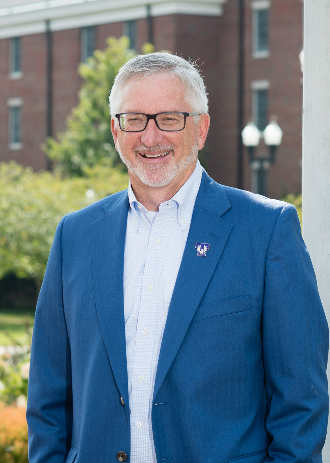 A vertically orientated photo of President Phil Oldham standing and smiling