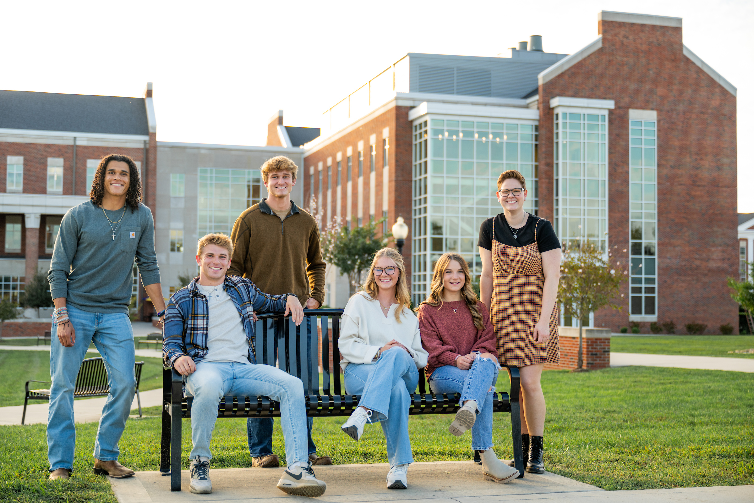 students sitting together on a bench, and standing beside the bench, in front of the Laboratory Science Commons building