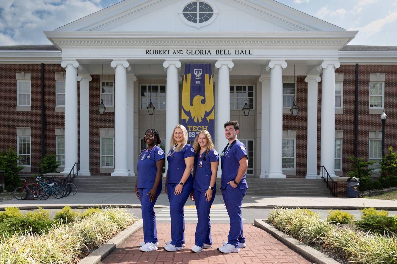 4 nursing students standing outside Bell Hall smiling
