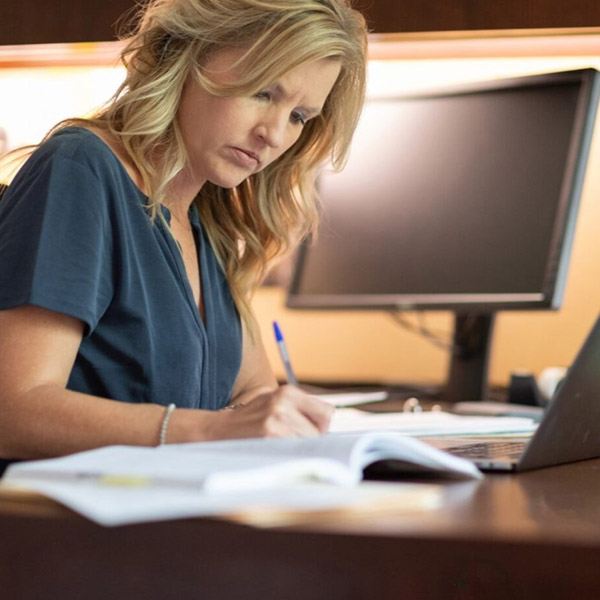 Dr. Elizabeth Ramsey working at her desk writing in a notebook.