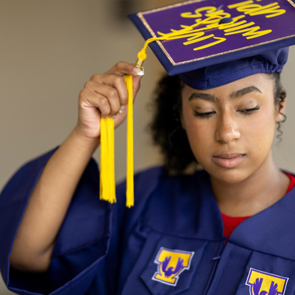 A student in a graduation gown posing for the camera.