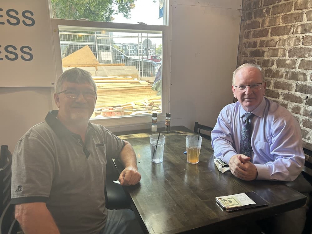 Two people sit across from each other at a wooden table in a restaurant.