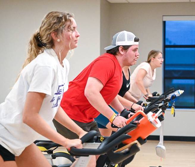 A group of students paticipating in an indoor cycling class.