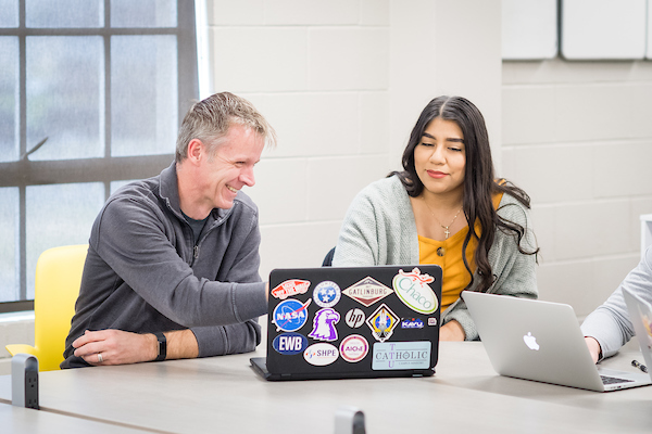 Image of an advisor meeting with a student and looking at a laptop screen.