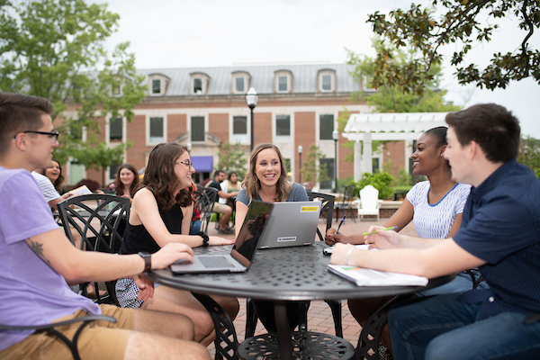 Photo of five students sitting at a table on Centennial Plaza
