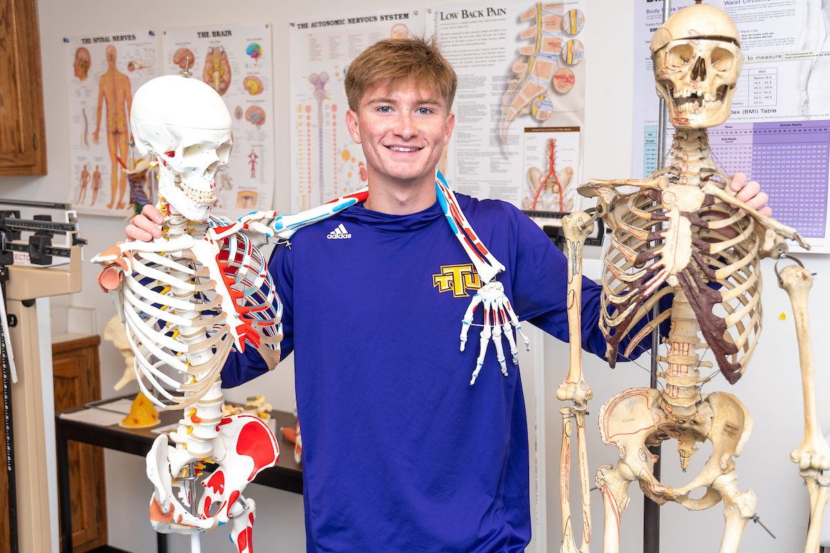 Carter Bradford poses with two skeletons
