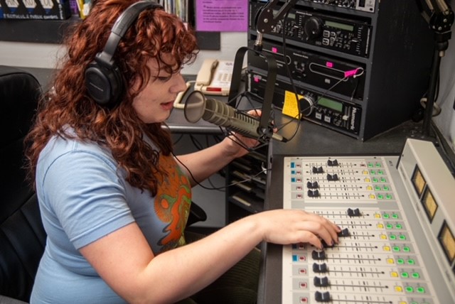 A DJ sits in the broadcasting booth