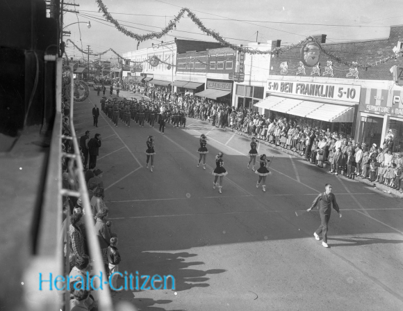 1960 Photo of Cookeville Christmas parade with baton twirlers and a band marching down Broad Street in front of the 5-10.