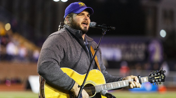 Jake Hoot singining playing the guitar and singing the national anthem at a TTU football game.