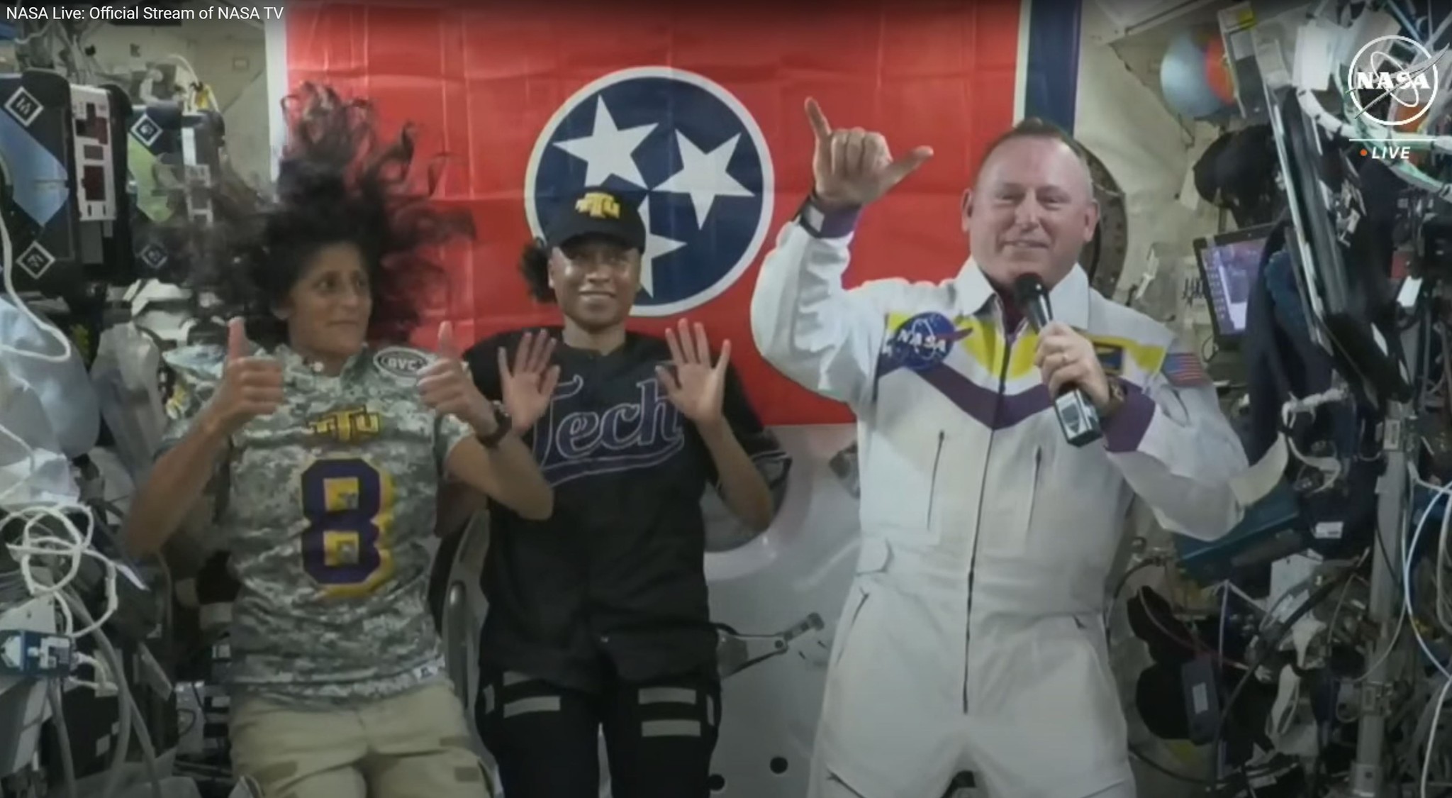 Astronauts Suni Williams and Jeanette Epps and don Tech football and baseball jerseys to show their support for Wilmore’s alma mater. Wilmore has purple and gold on his jumpsuit.
