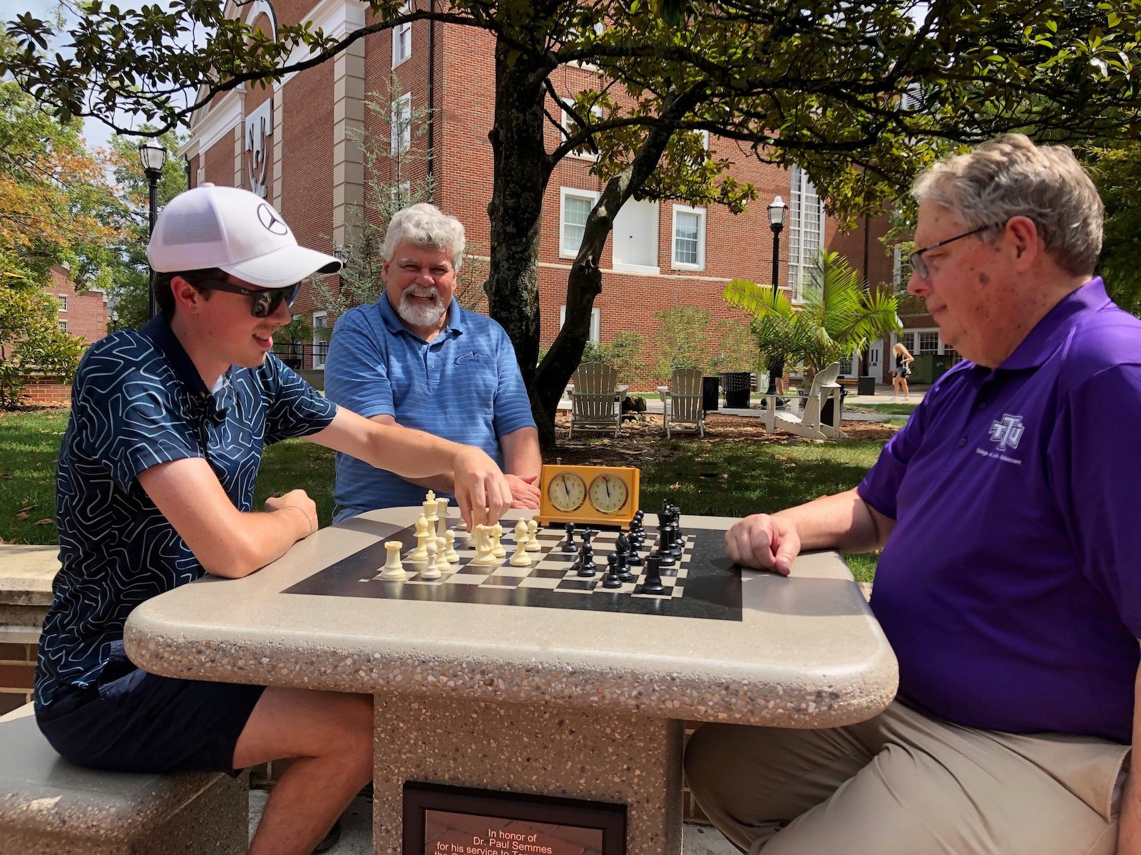 Dean Semmes and a member of the chess club play at the table while Dean Roberts watches on.